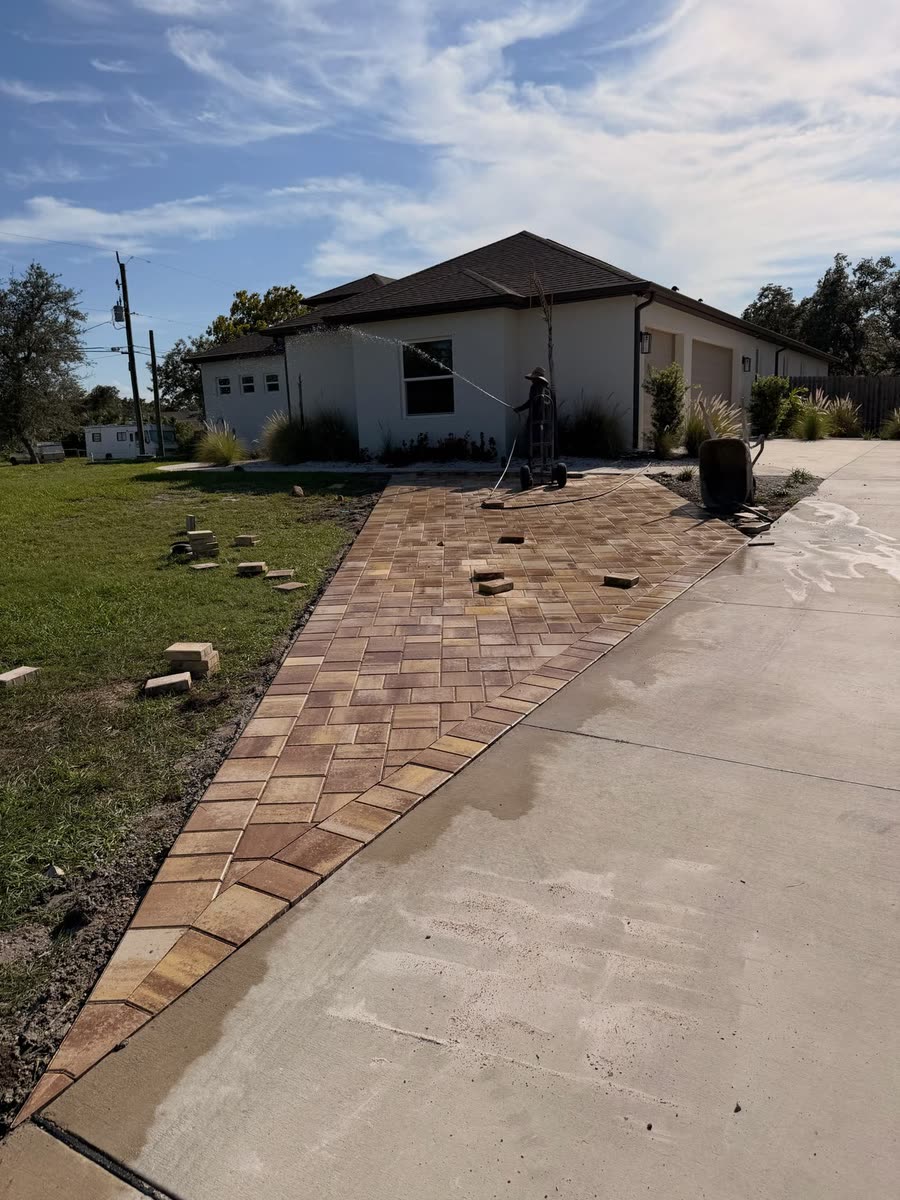 The same driveway extension from the street, pavers running up beside the concrete.