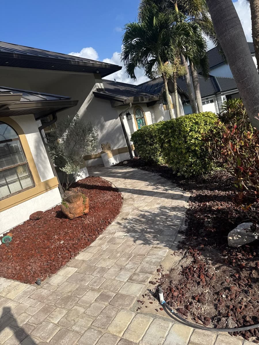 A paver path between mulch beds along the side of a house.